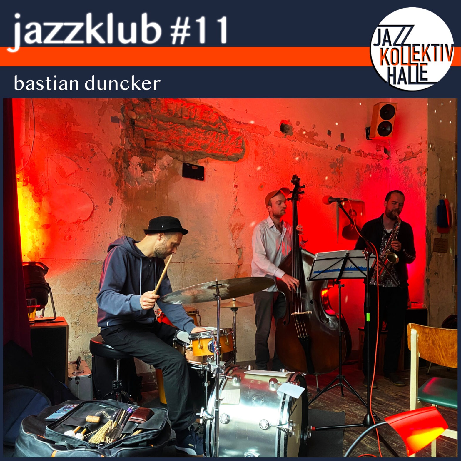 Ein Episodenbild. Oben links steht weiß auf dunkelblauem Hintergrund: "jazzklub #11". Darunter befindet sich ein orangener Balken unter dem der Name "bastian duncker" steht (wieder weiß auf blau). In der rechten oberen Ecke befindet sich das Logo des Jazzkollektivs Halle (weißer Kreis, in dem die Worte "JAZZ", "KOLLEKTIV" und "HALLE" untereinander stehen. Darunter füllt ein Foto eines Jazztrios die unteren vier Fünftel des Bildes. Die Band besteht aus einem Schlagzeuger (links), einem Kontrabassisten (MItte) und einem Saxophonisten (rechts). In der unteren linken Ecke sind diverse Schlagwerkzeuge (Besen, Sticks, e.t.c.) des Schlagzeugers zu sehen, die auf der Hülle der Basstrommel liegen. Die Wand hinter der Band ist teilweise unverputzt und wird rot und gelb angestrahlt. Außerdem tanzen in der rechten obreren Ecke die Reflexionen einer Diskokugel. In der rechten unteren Ecke befinden sich eine rote Lampe und ein, vom Foto angeschnittener, Stuhl mit grüner Sitzfläche.